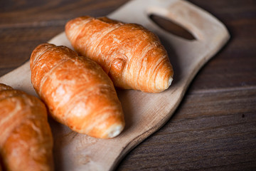Close up view of several croissants on confectioner's wooden board. Sweet for breakfast.