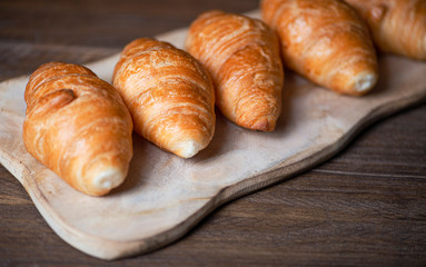 Close up view of several croissants on confectioner's wooden board. Sweet for breakfast.