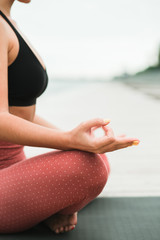 Asian young girl meditating outdoors on the pier by the lake.