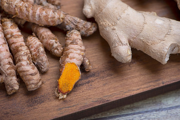 Turmeric root on kitchen cutting board. Spice for health and ingredient of Indian cuisine.