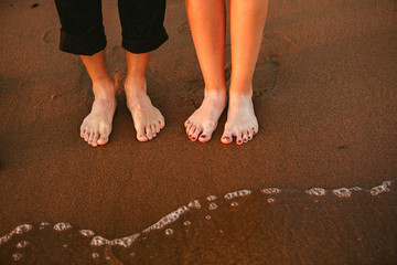 Front view of wedding couple's feet standing on the sandy beach.