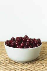 A plate full of fresh cherries on a natural wicker napkin