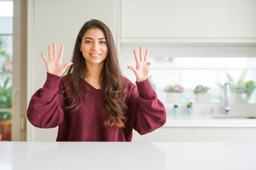Young beautiful woman at home showing and pointing up with fingers number nine while smiling...