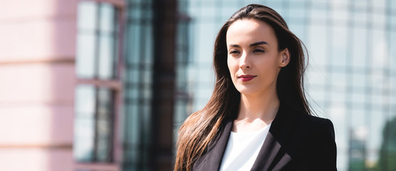 Fototapeta premium beautiful, positive businesswoman smiling and looking away while standing on rooftop
