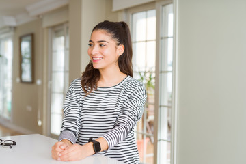Young beautiful woman at home looking away to side with smile on face, natural expression. Laughing confident.
