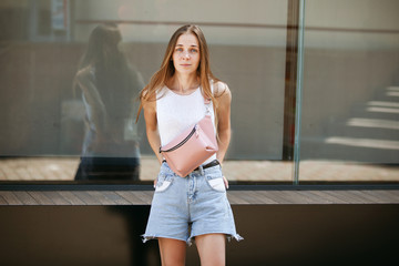 Beautiful slim girl in denim shorts looks into the camera in surprise.