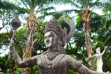 Vientiane, Laos: View on ancient sculpture in Buddha park with palm tree background