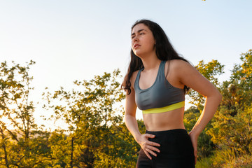 Naklejka na ściany i meble A young athletic woman experiences lower back or abdominal pain while exercising. The concept of sports and sports injuries