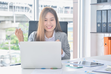 Asian business working with laptop and having success raising arms after get good news