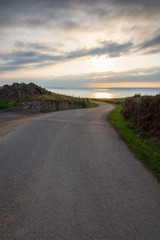 Vertical view of lonely local road with sunset on the sea in Cantabria, Spain, Europe