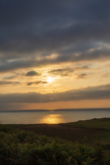 Fototapeta premium Vertical landscape of meadows and coast with sunset on the sea in Cantabria, Spain, Europe