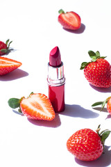 Red lipstick beauty concept close up with fresh strawberries on the white background. 