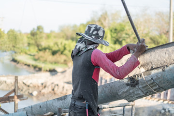 Cement mixer truck pouring cement into a foundation for bridge building with construction workers...