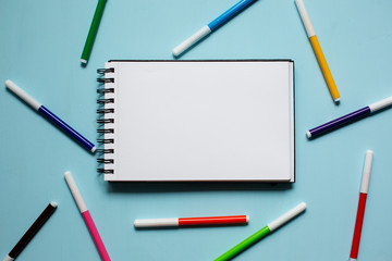 Notepad and markers on blue wooden background top view
