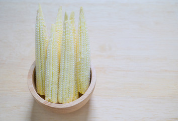 oung raw baby corn vegetables on wooden bowl.