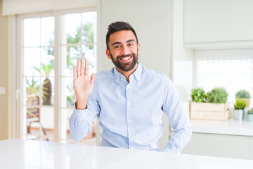 Handsome hispanic business man Waiving saying hello happy and smiling, friendly welcome gesture