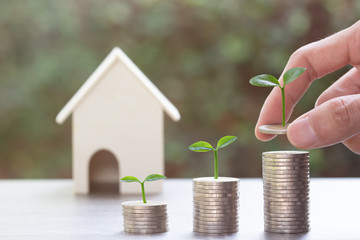 Saving money or property investment concept. A man hand putting coin into rising stack of coins...
