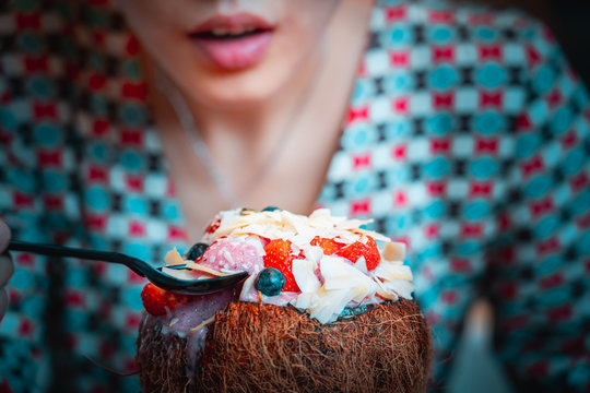 Woman Eating Acai Bowl In Coconut Plate, Close Up.