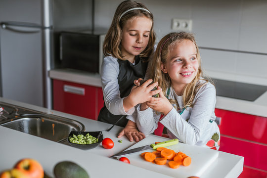 Little girl demonstrating half of ripe avocado to camera while standing in the kitchen looking at camera