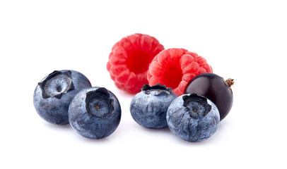 Fresh ripe berries in closeup on white background. Raspberries with blueberries and black currant.