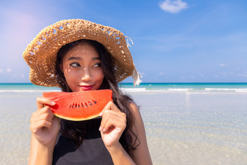 Beautiful young asian woman holding watermelon, looks at copy space in summer season at beautiful...