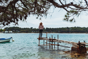 Fototapeta na wymiar woman standing on fishing pier looking at not calm sea