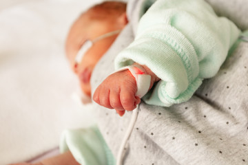 Obraz na płótnie Canvas Newborn hand and heart monitor attached closeup