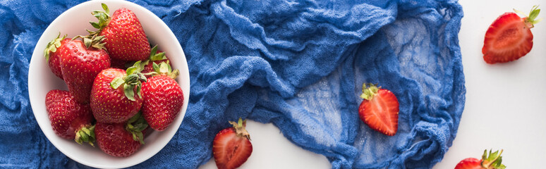 panoramic shot of fresh and ripe strawberries on bowl with blue cloth