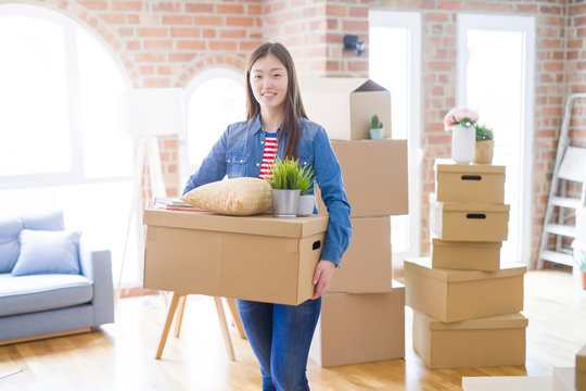 Beautiful asian young woman holding boxes, smiling happy moving to a new home