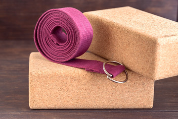 Two cork blocks  and violet yoga strap for doing yoga on wooden floor. Yoga props background.
