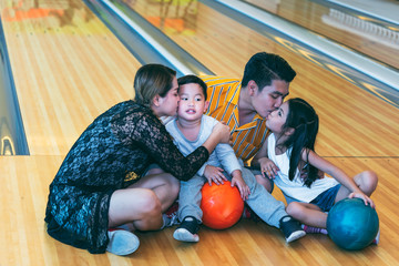 Fototapeta na wymiar Asian parents, daughters and sons, do activities together on vacation With play bowling, to sport recreation and family concept.