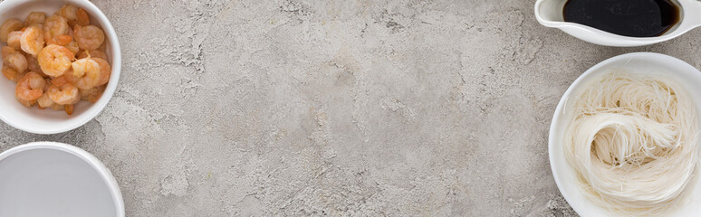 panoramic shot of shrimps, soy sauce and noodles on table