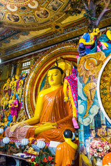 Fototapeta premium Buddha statue inside Gangaramaya Temple, Colombo, Sri Lanka. Vertical.