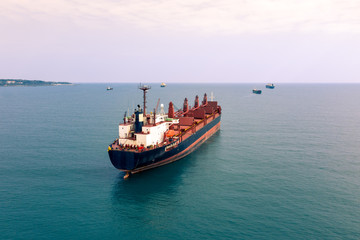 Aerial view of high-speed sea vessel for transportation of a cargo vessel at high speed is drifting near the seaport of the city at sunset. Ship on the background of blue sea water. Import, export