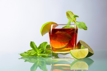 Cocktail with lime and mint on a glass table.