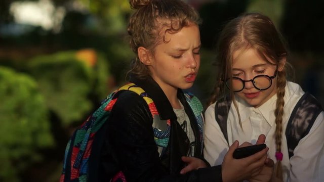 Girlfriends go to school and share their secrets with each other. Children and gadgets, two classmates chatting fun
