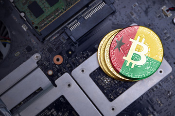 golden bitcoins with flag of guinea bissau on a computer electronic circuit board. bitcoin mining...