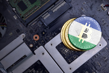 golden bitcoins with flag of lesotho on a computer electronic circuit board. bitcoin mining concept.