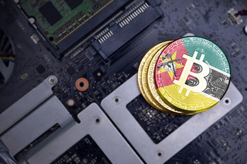 golden bitcoins with flag of mozambique on a computer electronic circuit board. bitcoin mining...