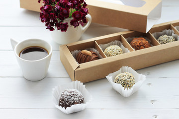 Chocolate candies, a cup of coffee and a bunch of flowers for Valentine's Day on wooden table.