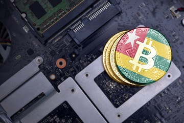 golden bitcoins with flag of togo on a computer electronic circuit board. bitcoin mining concept.