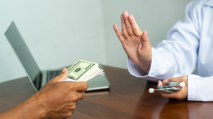 The patient's hand is sending money to the doctor for bribery in medical treatment.