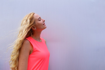 Young blonde girl in dress looking up against white wall.