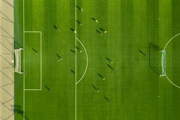 Aerial view from below of a large green football field with white lined lines and players playing a match. Playing football at the stadium. Professional soccer players are located on the playing field