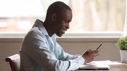 Smiling african american man holding smartphone using apps texting message