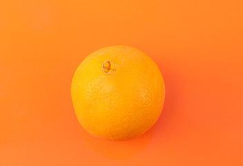 Top view of a ripe orange on an orange background - Freshly harvested orange
