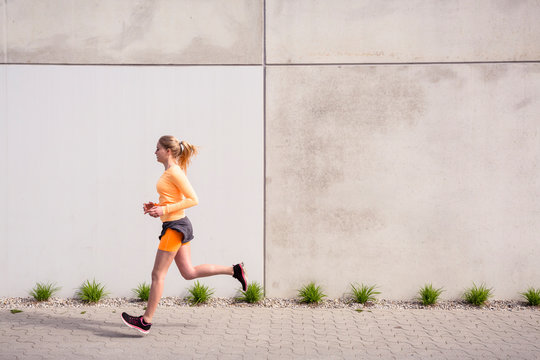 Olympia Park, Munich, Bavaria, Germany: A young female runner running through the olympic village in the morning.