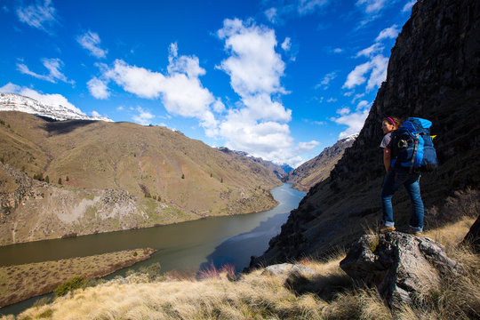 A young woman with a backpack stands overlooking the scenic Snake River in Hells Canyon on an overlook near the Allison Creek Trail (No. 514).