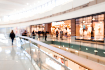 Blurred big sales on Black Friday. A long light floor in the mall with shops for buyers. Sale of...