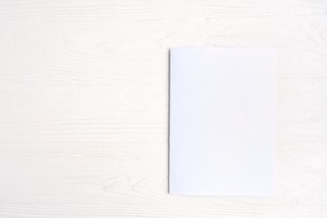 Blank sheet of white paper for design banner or card on textured neutral background, selective focus. Clear page with empty space for image or text on wooden white backdrop. Mockup concept 